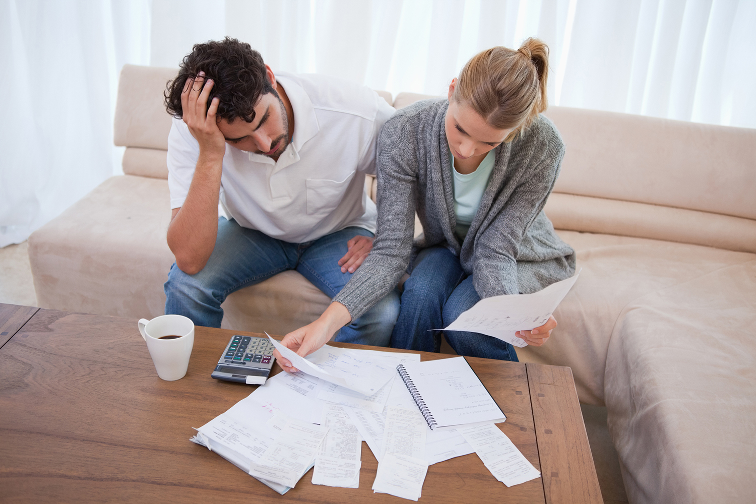 A couple with papers and a calculator looking concerned to illustrate debt, money, finance